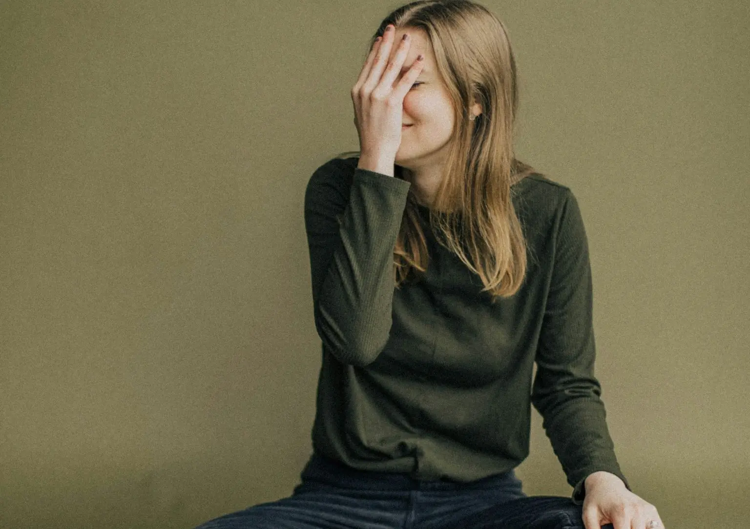 woman in black long sleeve shirt and blue denim jeans sitting on brown wooden chair